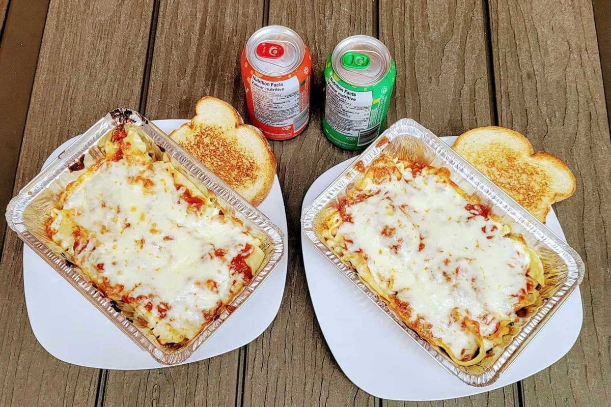 Two Pasta Dishes with Two Garlic Toasts and Two Cans of Pops