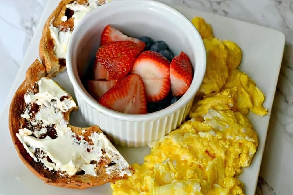 Deux Oeufs Pochés Avec bagel, fromage cottage et fruits frais /Two Poached Eggs With Bagel, Cottage Cheese and Fresh Fruits
